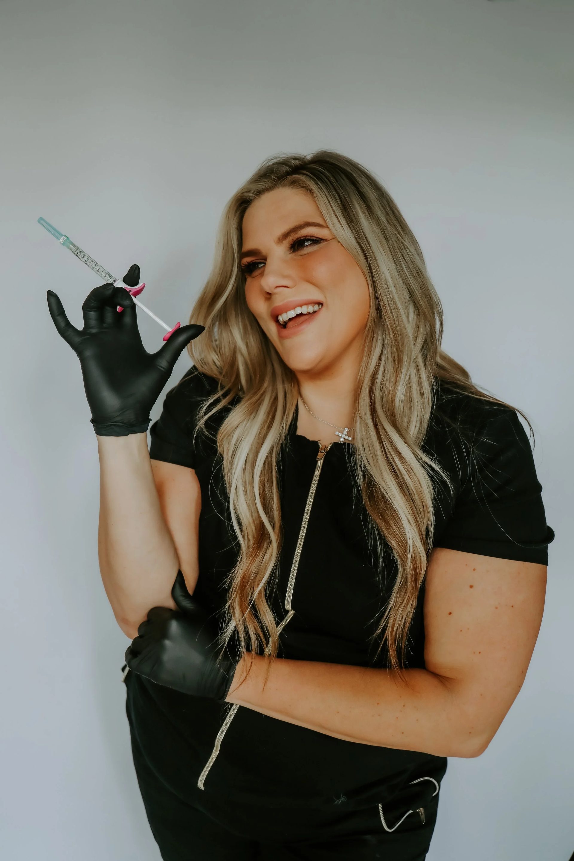Registered nurse injector in black gloves holding a syringe at All About Monroe in Demorest, Georgia